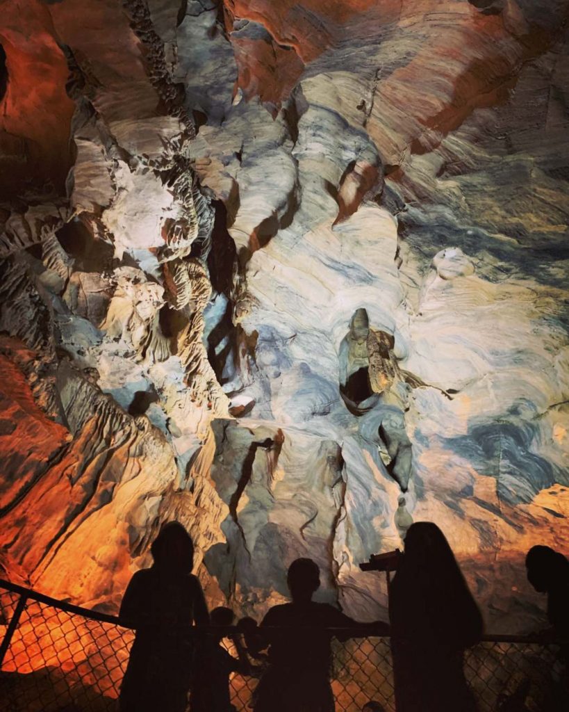Silhouette of a family of four against beautiful rock formations inside California Cavern State Historic Landmark.
